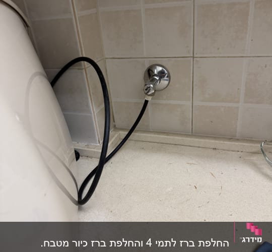 צינור שחור מחובר לשסתום על קיר אריחים